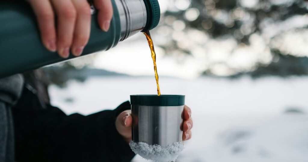 man pouring out coffee from travel coffee mug into a cup in Ice place